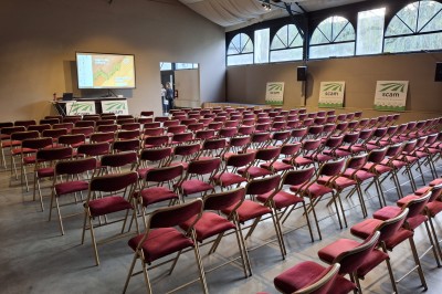 Cour intérieure d'un château avec pelouse, tables en bois, bâtiments en pierre et tours sous un ciel dégagé.