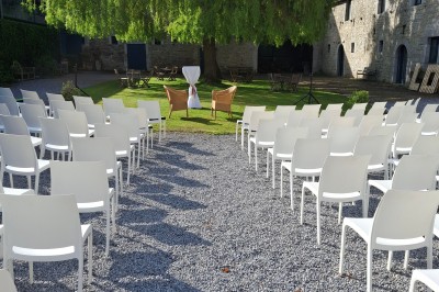 Cour intérieure d'un château avec pelouse, tables en bois, bâtiments en pierre et tours sous un ciel dégagé.