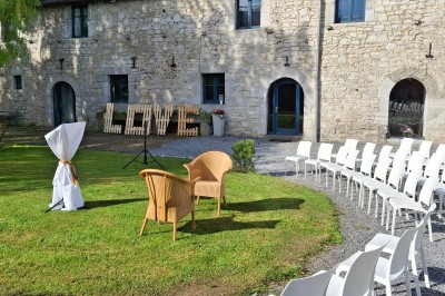 Cour intérieure d'un château avec pelouse, tables en bois, bâtiments en pierre et tours sous un ciel dégagé.