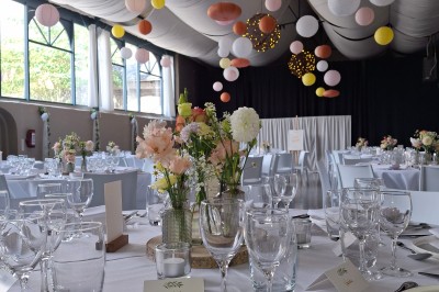 Cour intérieure d'un château avec pelouse, tables en bois, bâtiments en pierre et tours sous un ciel dégagé.