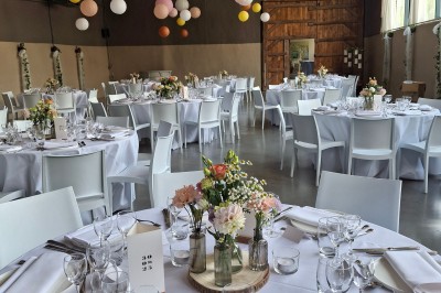 Cour intérieure d'un château avec pelouse, tables en bois, bâtiments en pierre et tours sous un ciel dégagé.