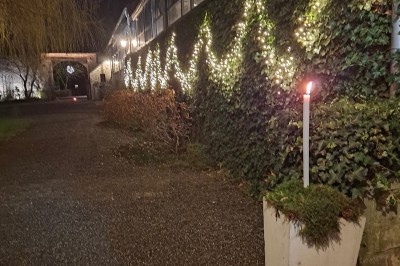 Cour intérieure d'un château avec pelouse, tables en bois, bâtiments en pierre et tours sous un ciel dégagé.