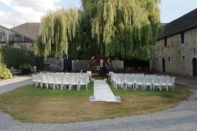 Cour intérieure d'un château avec pelouse, tables en bois, bâtiments en pierre et tours sous un ciel dégagé.