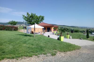 Bâtiment à un étage avec toit en tuiles, entouré de chemins, de pelouse et de vignes en arrière-plan.