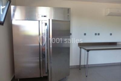 Bâtiment à un étage avec toit en tuiles, entouré de chemins, de pelouse et de vignes en arrière-plan.