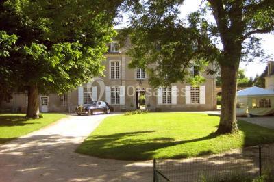 Miniature Location salle Gonneville-en-Auge (Calvados) - Château de Merville #2 Salle à manger rustique avec murs en pierre, table en bois, chaises assorties et porte-fenêtre donnant sur l'extérieur.