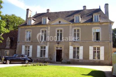 Miniature Location salle Gonneville-en-Auge (Calvados) - Château de Merville #3 Salle à manger rustique avec murs en pierre, table en bois, chaises assorties et porte-fenêtre donnant sur l'extérieur.