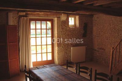 Miniature Location salle Gonneville-en-Auge (Calvados) - Château de Merville #24 Salle à manger rustique avec murs en pierre, table en bois, chaises assorties et porte-fenêtre donnant sur l'extérieur.