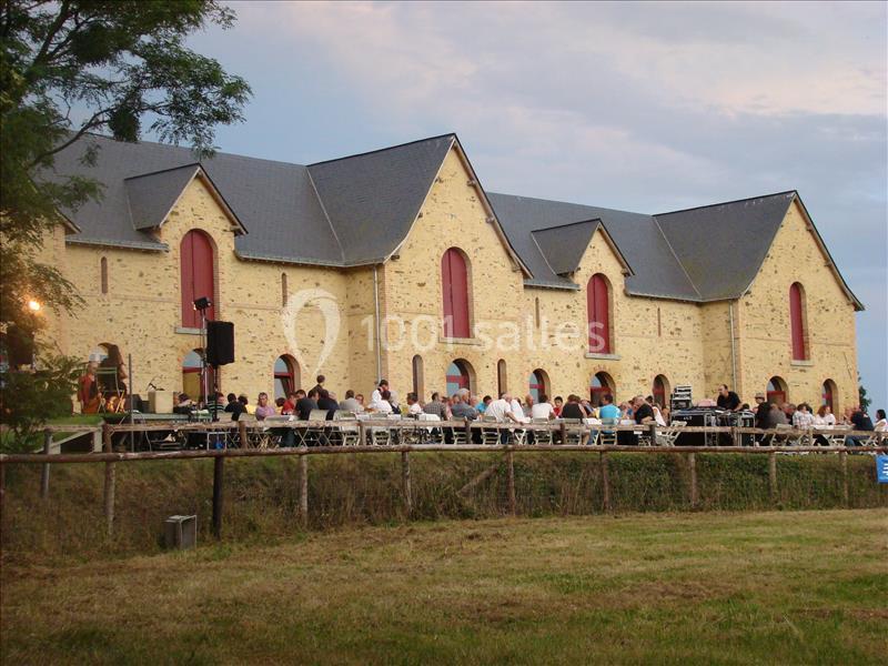 Un bâtiment en pierre avec des fenêtres rouges, entouré de personnes assises à l'extérieur lors d'un événement.
