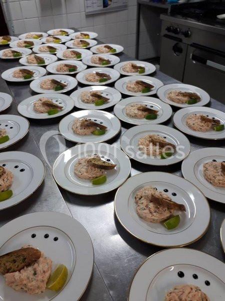Assiettes alignées sur un plan de travail, contenant du tartare de saumon, une tranche de pain et un quartier de citron.