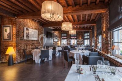 Jambon sur support, bol de tartare et croûtons disposés sur une table devant un mur en briques.