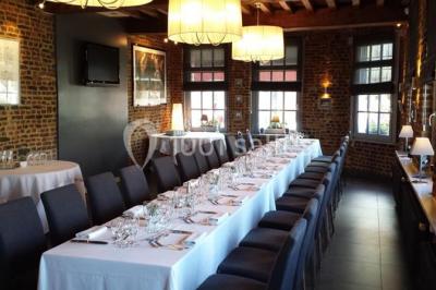 Jambon sur support, bol de tartare et croûtons disposés sur une table devant un mur en briques.