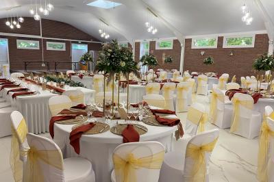 Miniature Location salle Paillencourt (Nord) - Le Canotier #2 Table en bois décorée de bougies, fleurs et feuillage, entourée de chaises, sous une arche végétale dans une salle lumineuse.