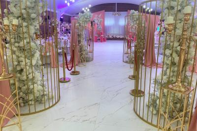 Miniature Location salle Paillencourt (Nord) - Le Canotier #15 Table en bois décorée de bougies, fleurs et feuillage, entourée de chaises, sous une arche végétale dans une salle lumineuse.