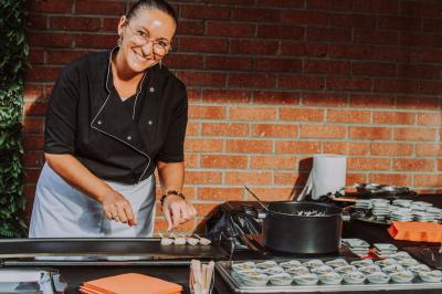 Miniature Location salle Paillencourt (Nord) - Le Canotier #18 Table en bois décorée de bougies, fleurs et feuillage, entourée de chaises, sous une arche végétale dans une salle lumineuse.