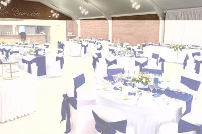 Miniature Location salle Paillencourt (Nord) - Le Canotier #21 Table en bois décorée de bougies, fleurs et feuillage, entourée de chaises, sous une arche végétale dans une salle lumineuse.