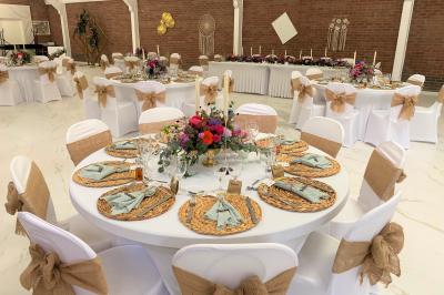 Miniature Location salle Paillencourt (Nord) - Le Canotier #31 Table en bois décorée de bougies, fleurs et feuillage, entourée de chaises, sous une arche végétale dans une salle lumineuse.