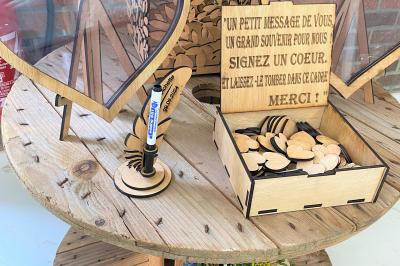 Miniature Location salle Paillencourt (Nord) - Le Canotier #33 Table en bois décorée de bougies, fleurs et feuillage, entourée de chaises, sous une arche végétale dans une salle lumineuse.