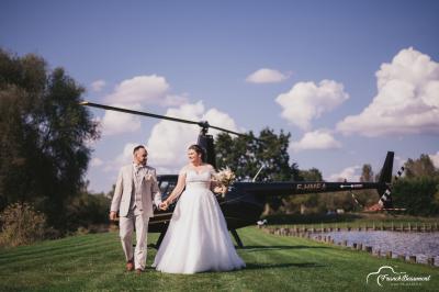 Miniature Location salle Paillencourt (Nord) - Le Canotier #38 Table en bois décorée de bougies, fleurs et feuillage, entourée de chaises, sous une arche végétale dans une salle lumineuse.