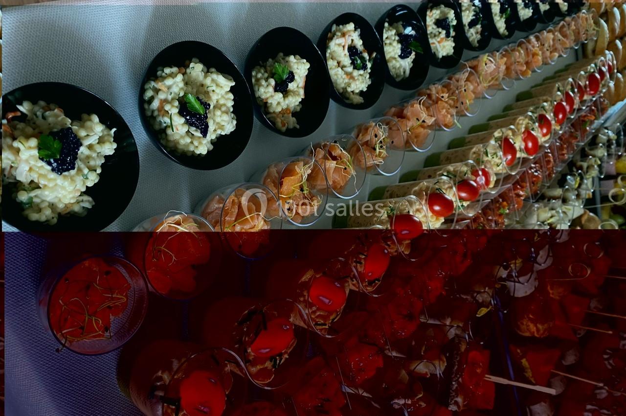 Buffet avec rangées de verrines et assiettes contenant des plats variés, dont du risotto et des garnitures colorées.