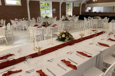 Salle de réception décorée avec des tables rondes blanches, nappes élégantes et chaises assorties, prête pour un événement.