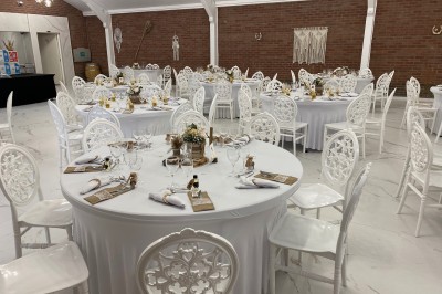 Tente blanche avec fenêtres en arc installée dans un jardin, entourée d'arbres et de pelouses sous un ciel dégagé.