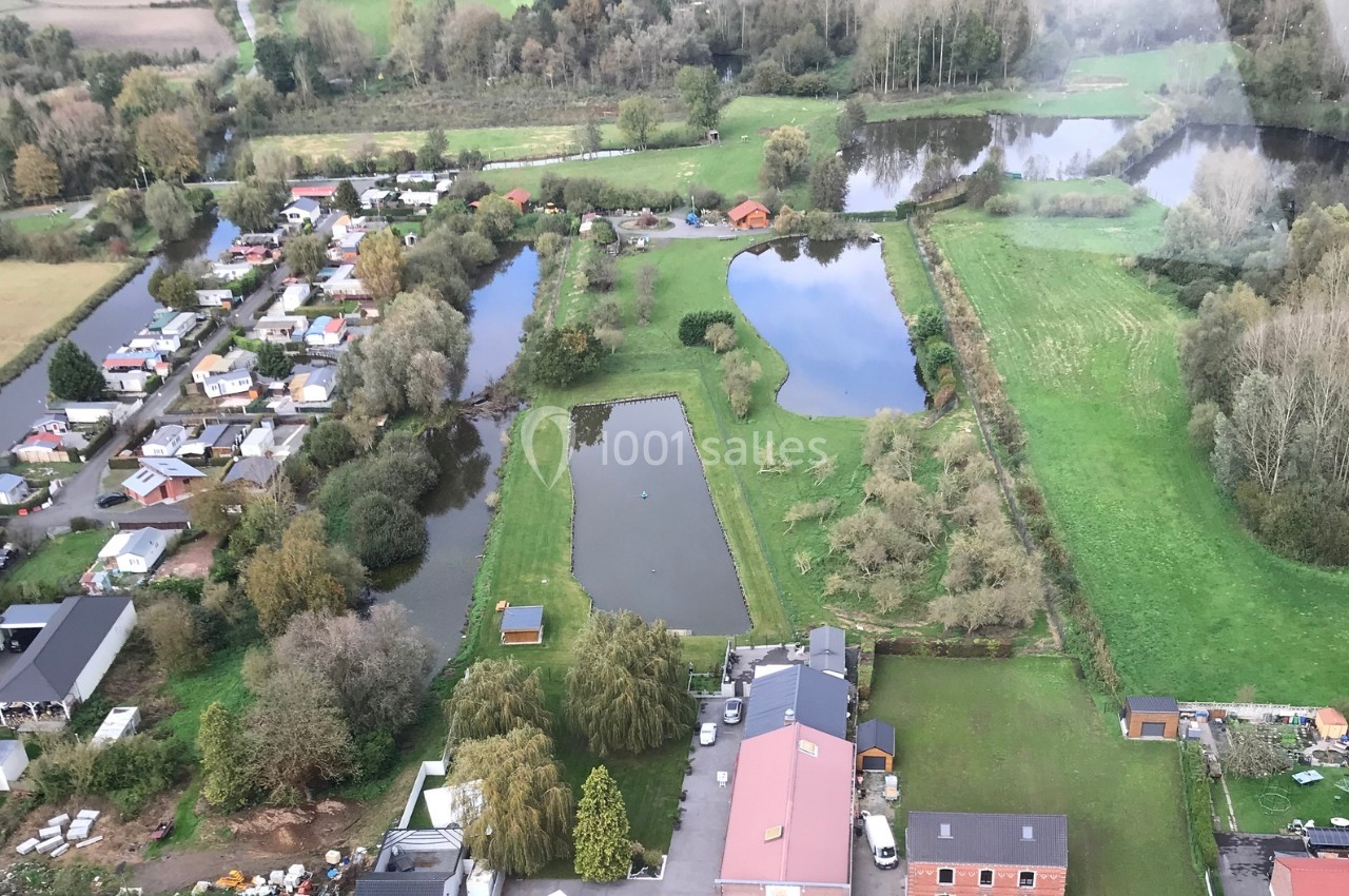 Vue aérienne d'un paysage rural avec étangs, prairies, arbres et habitations dispersées.