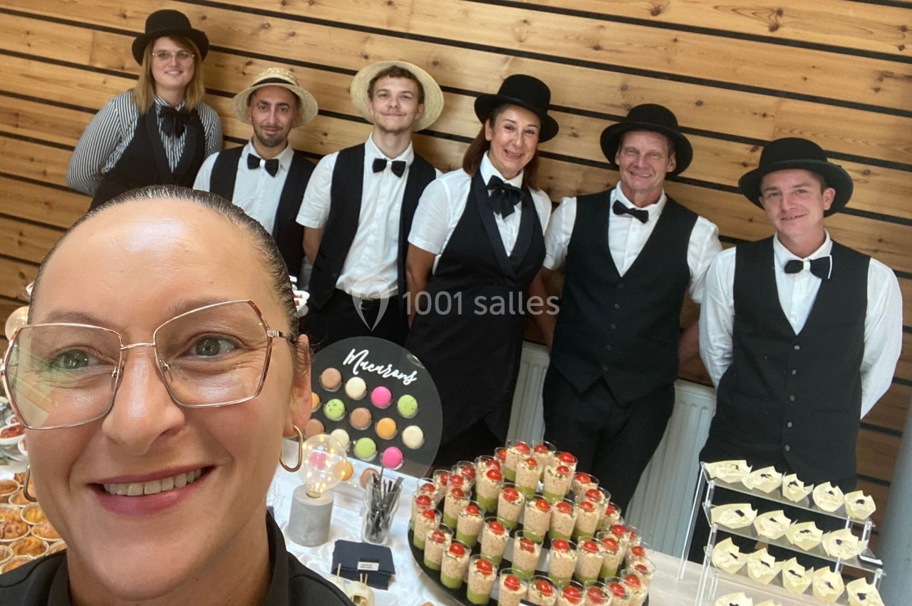 Un groupe de serveurs en uniforme posant derrière une table garnie de desserts variés.