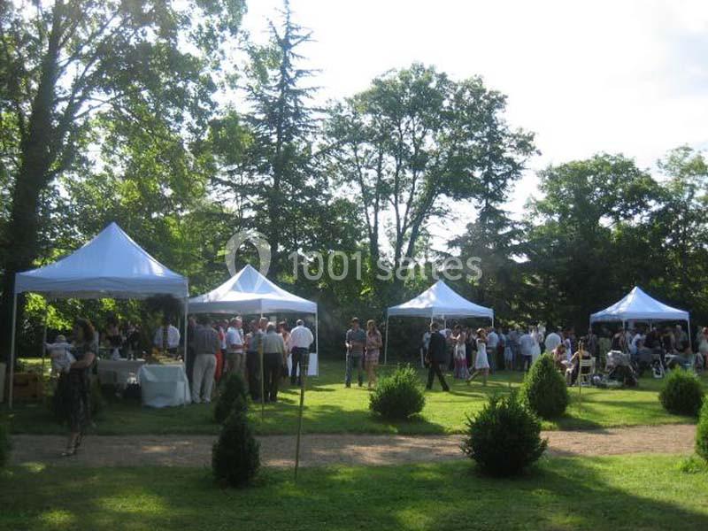 Des personnes rassemblées dans un jardin sous des tentes blanches lors d'un événement en plein air.