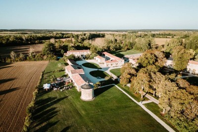 Bâtiment en pierre éclairé la nuit, avec un ciel bleu foncé en arrière-plan et un jardin sombre au premier plan.