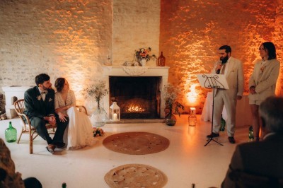 Bâtiment en pierre éclairé la nuit, avec un ciel bleu foncé en arrière-plan et un jardin sombre au premier plan.