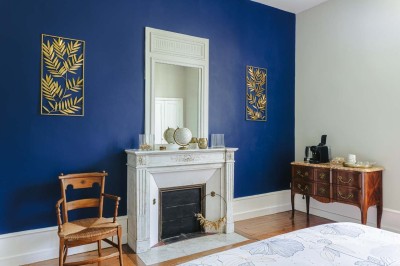 Bâtiment en pierre éclairé la nuit, avec un ciel bleu foncé en arrière-plan et un jardin sombre au premier plan.