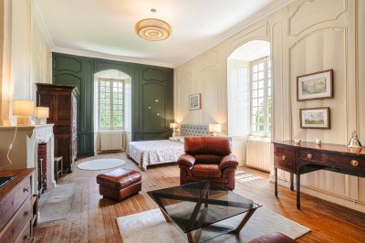 Bâtiment en pierre éclairé la nuit, avec un ciel bleu foncé en arrière-plan et un jardin sombre au premier plan.