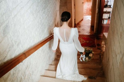 Bâtiment en pierre éclairé la nuit, avec un ciel bleu foncé en arrière-plan et un jardin sombre au premier plan.
