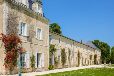 Bâtiment en pierre éclairé la nuit, avec un ciel bleu foncé en arrière-plan et un jardin sombre au premier plan.