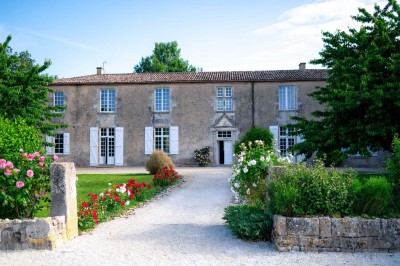 Bâtiment en pierre éclairé la nuit, avec un ciel bleu foncé en arrière-plan et un jardin sombre au premier plan.
