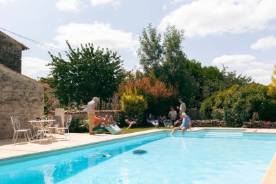 Bâtiment en pierre éclairé la nuit, avec un ciel bleu foncé en arrière-plan et un jardin sombre au premier plan.