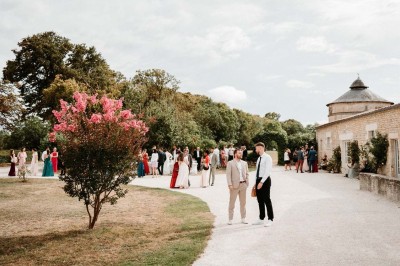 Bâtiment en pierre éclairé la nuit, avec un ciel bleu foncé en arrière-plan et un jardin sombre au premier plan.