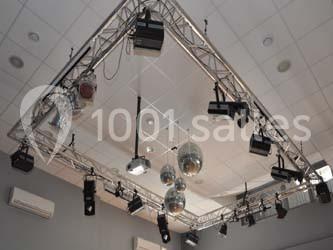 Structure métallique suspendue avec projecteurs et boules à facettes dans une salle au plafond blanc.