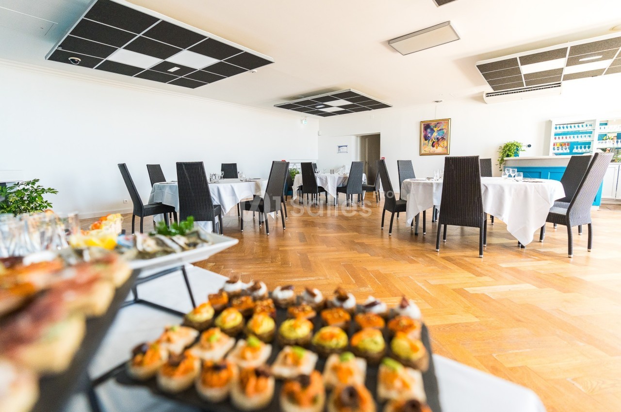 Salle de restaurant lumineuse avec tables dressées et un buffet de petits plats en premier plan.
