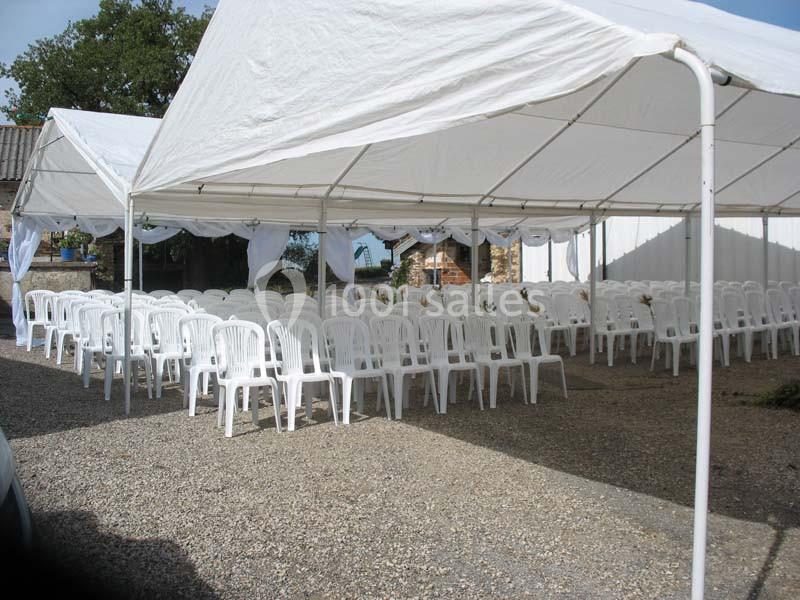 Tentes blanches montées en extérieur avec des rangées de chaises en plastique blanc disposées pour un événement.
