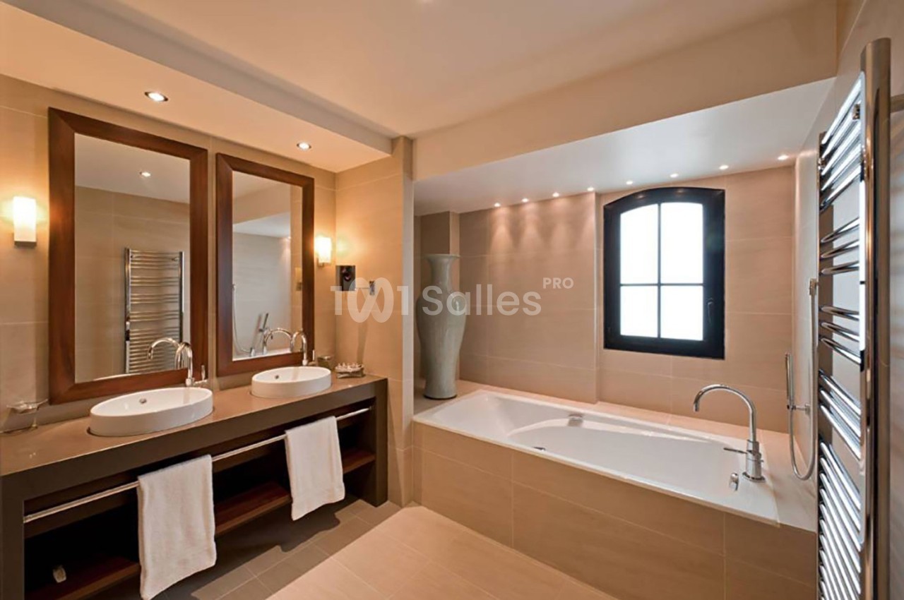 Salle de bain moderne avec double vasque, baignoire encastrée, miroir en bois et fenêtre en arche.