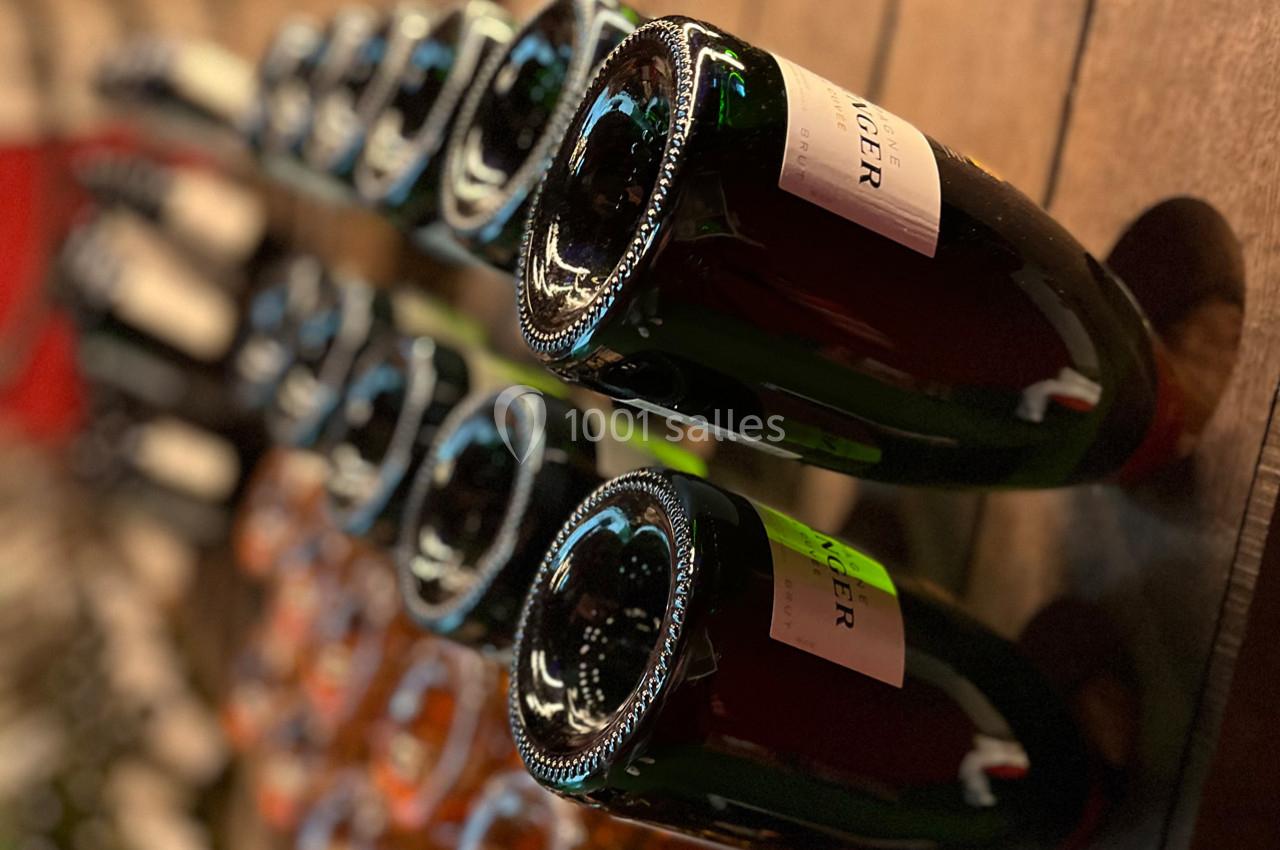 Bouteilles de vin ou de champagne entreposées horizontalement sur un présentoir en bois.