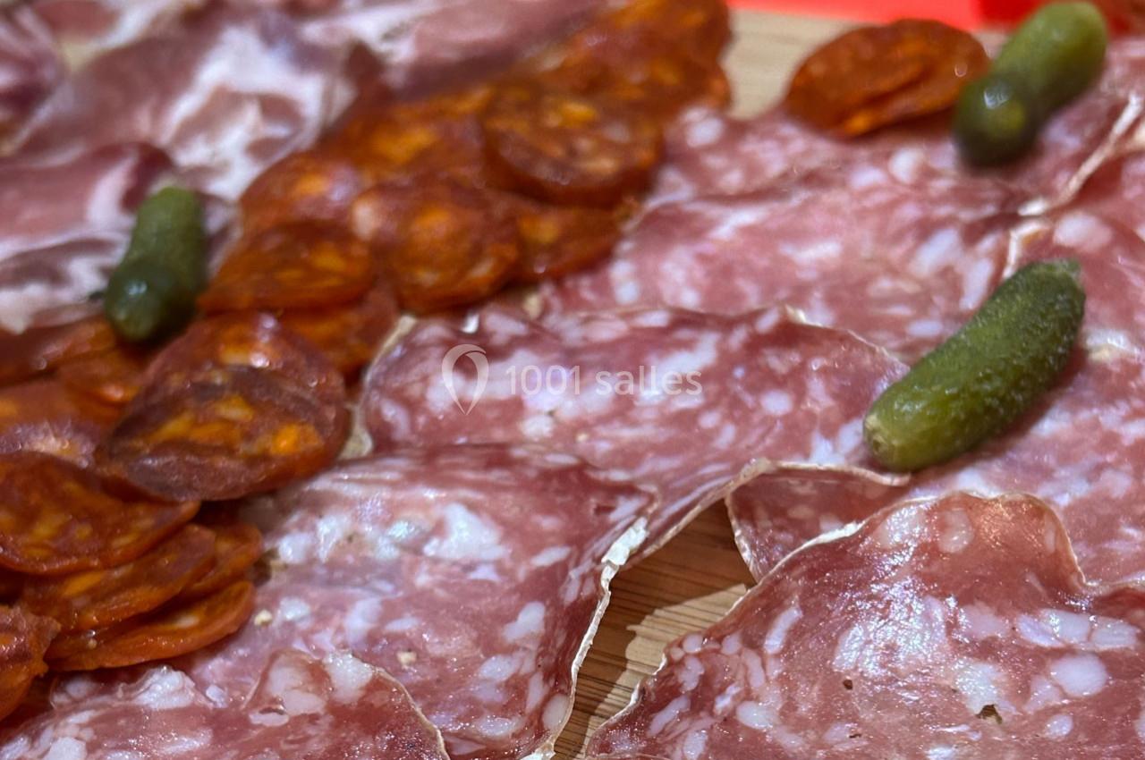 Plateau de charcuterie avec tranches de saucisson, chorizo et cornichons sur une planche en bois.