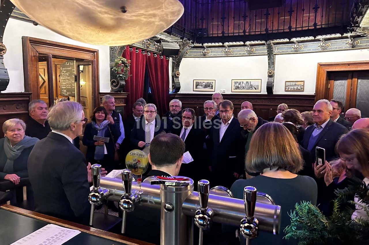 Un groupe de personnes rassemblées dans un bar ou une salle avec un décor ancien et des éléments en bois.