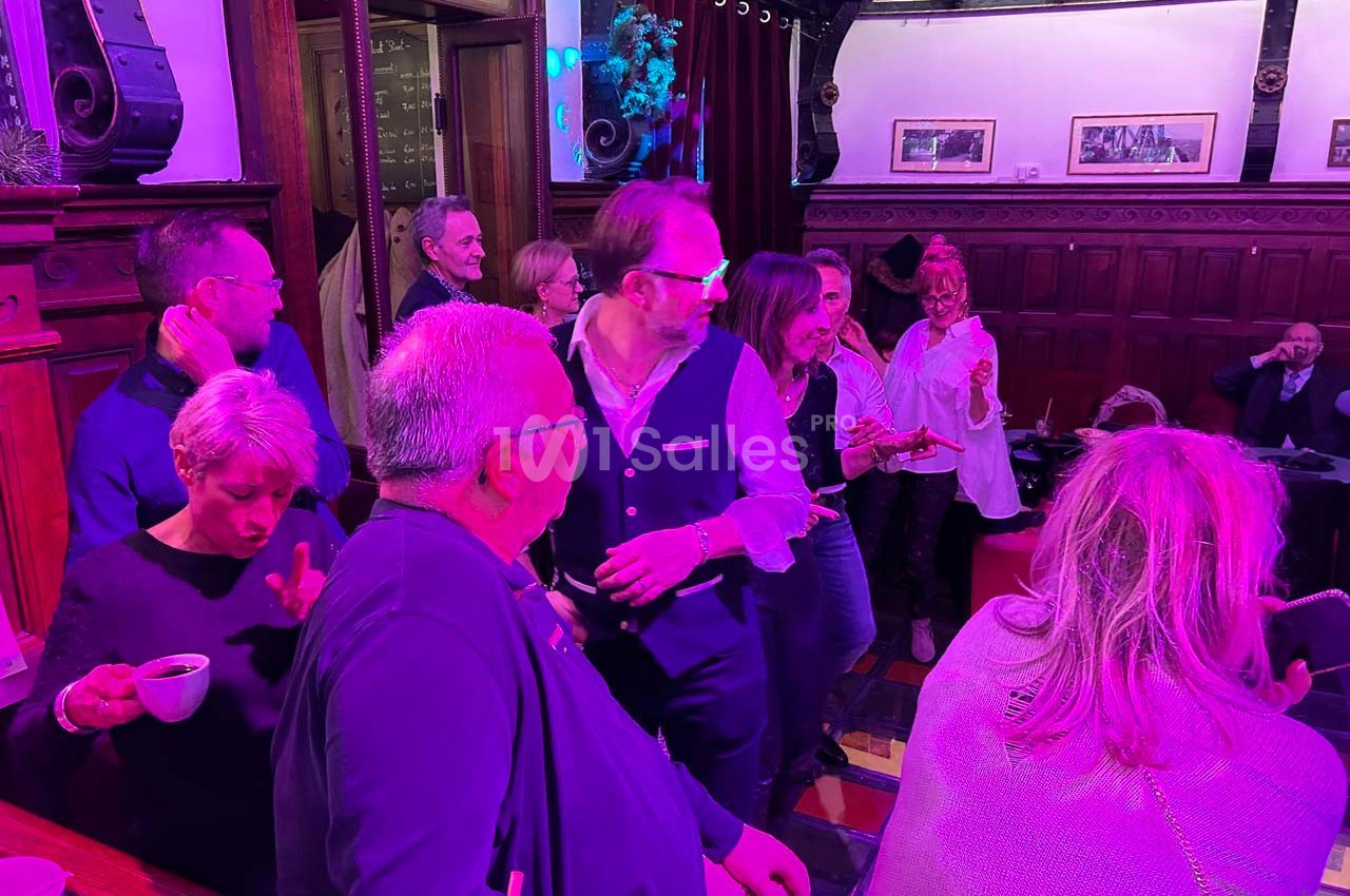 Des personnes discutent et partagent un moment convivial dans un intérieur chaleureux éclairé par des lumières colorées.
