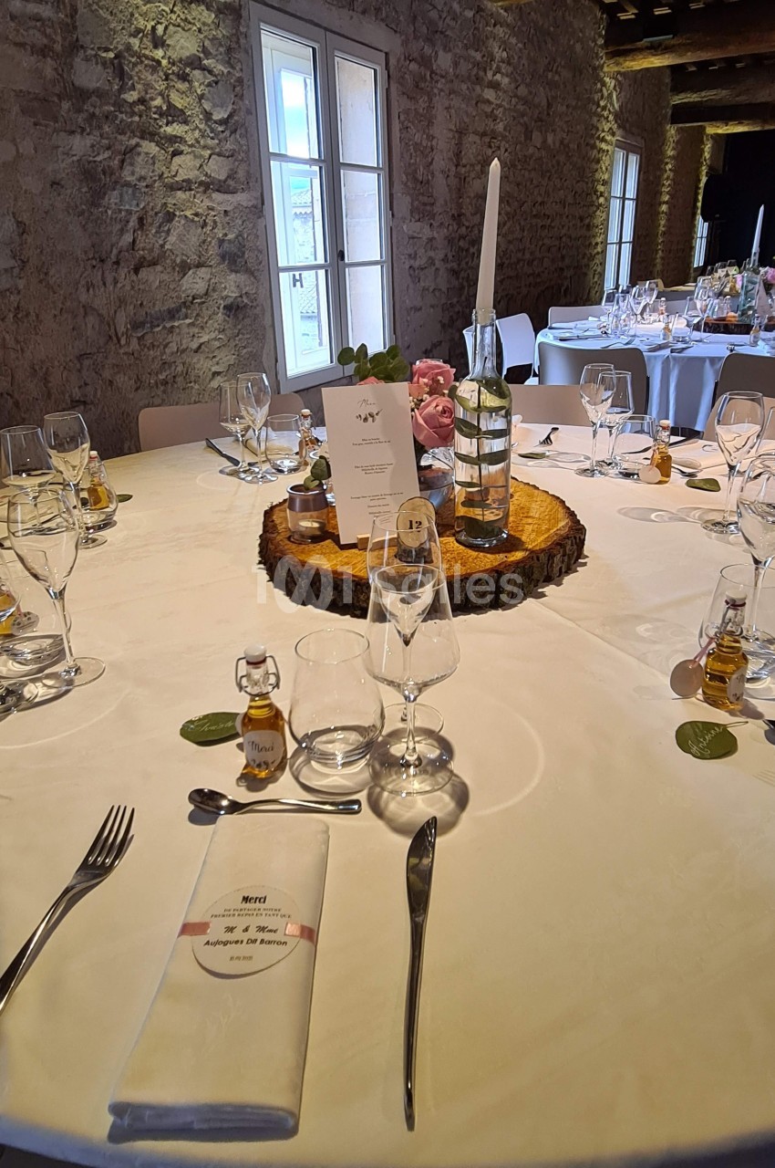 Table de réception décorée avec des éléments rustiques, bougie, menus, et petits flacons en guise de cadeaux invités.