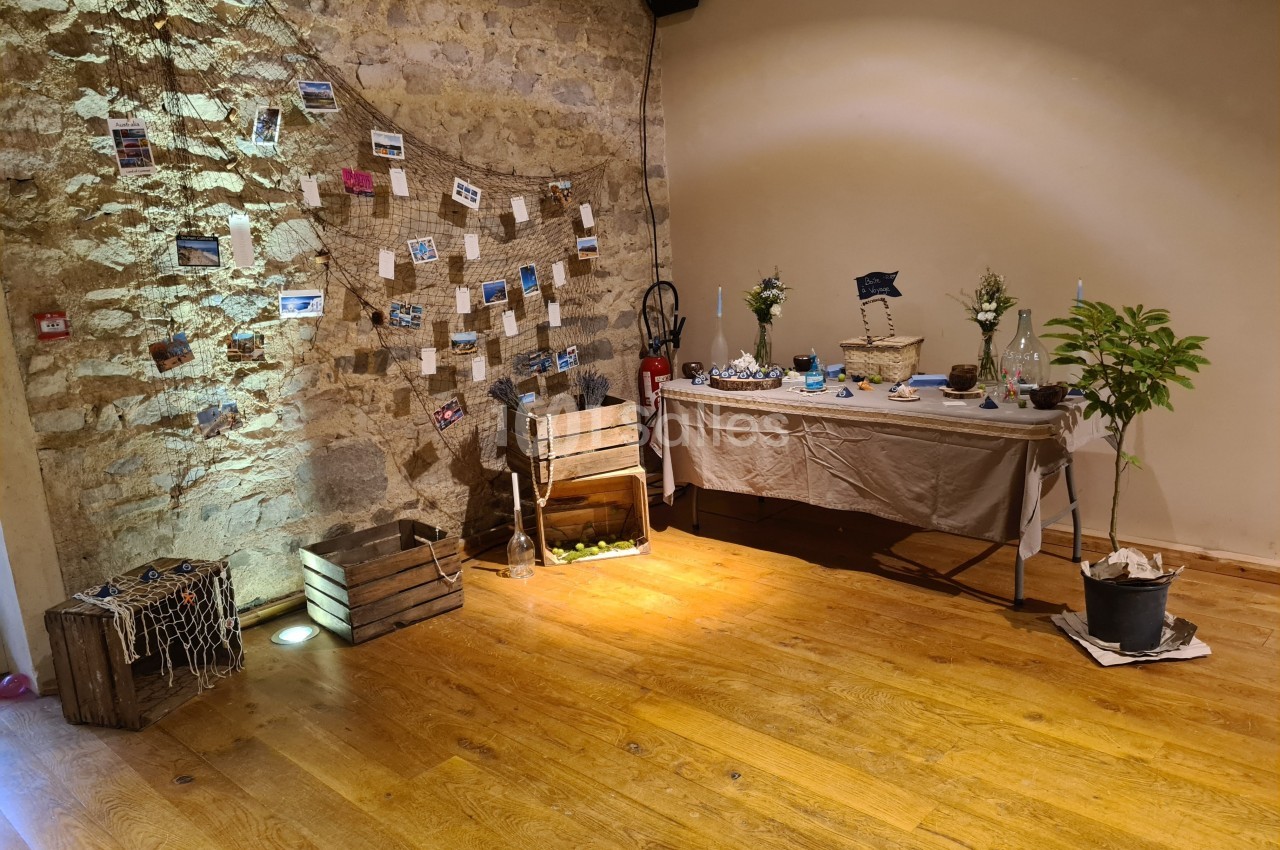 Décoration intérieure avec thème marin, comprenant des caisses en bois, un filet, des photos suspendues et une table dressée.