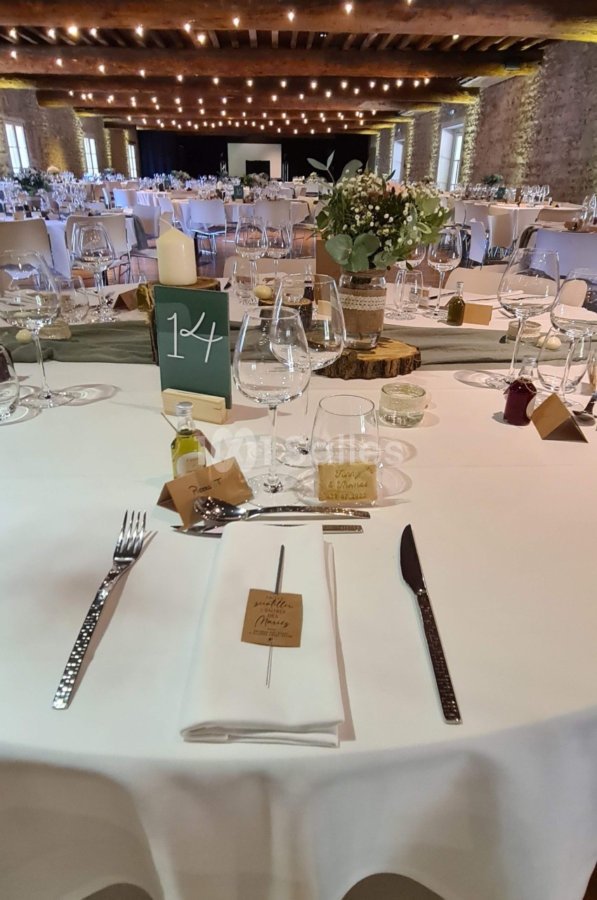 Table dressée pour un repas festif avec couverts, verres, décoration florale et numéro de table dans une salle éclairée.