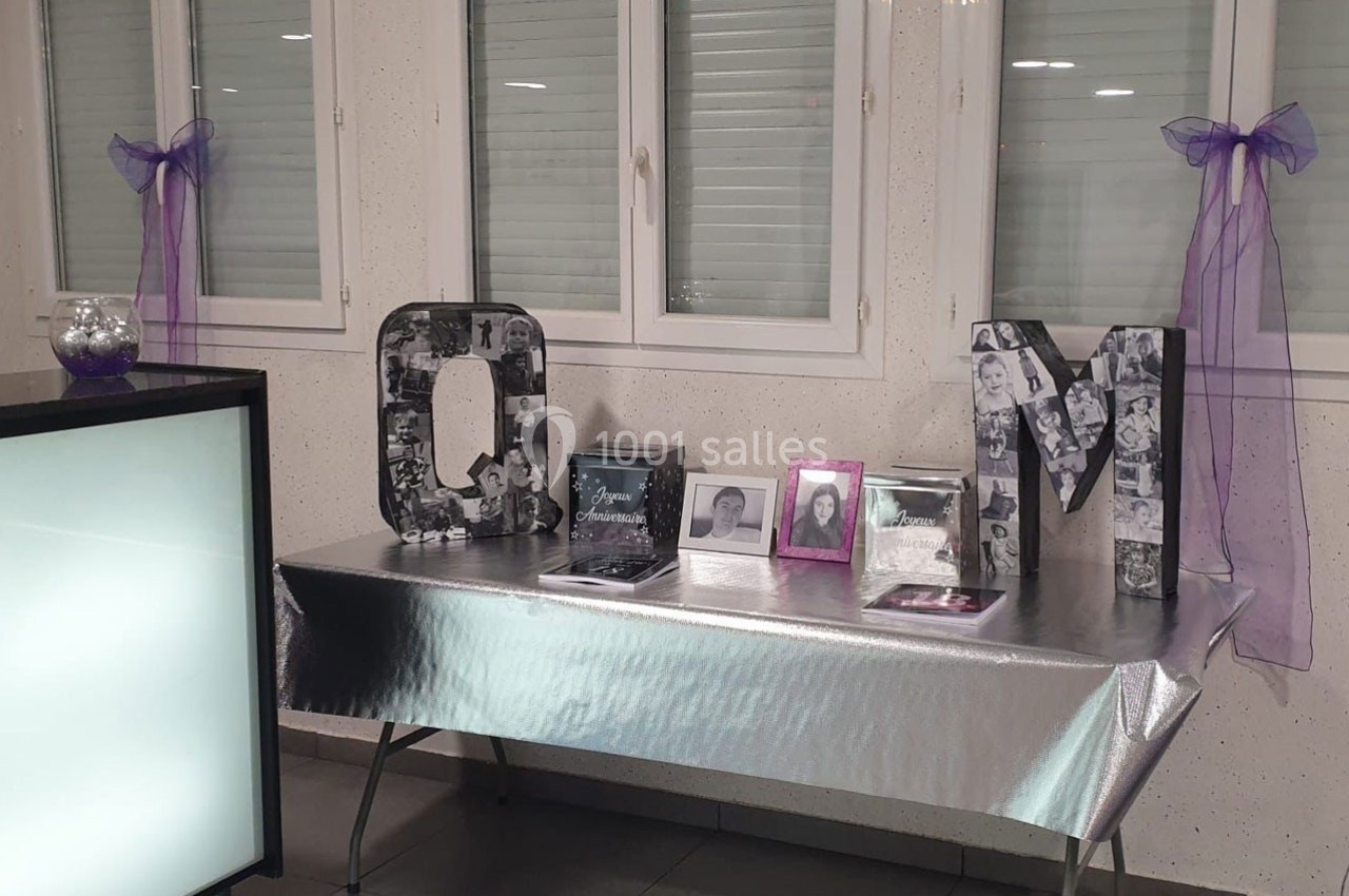 Table décorée avec des lettres ’Q’ et ’M’ ornées de photos, cadres photo et rubans violets sur les fenêtres.